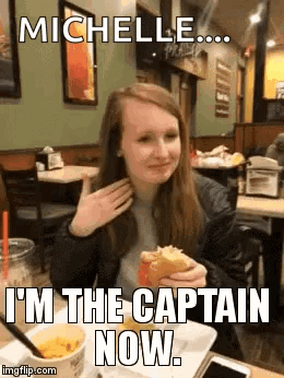 A Girl Is Sitting At A Table In A Restaurant Eating A Hamburger And Talking On A Cell Phone . GIF