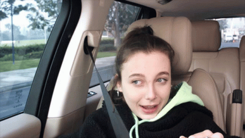 A Girl Is Sitting In The Back Seat Of A Car With A Seat Belt On GIF