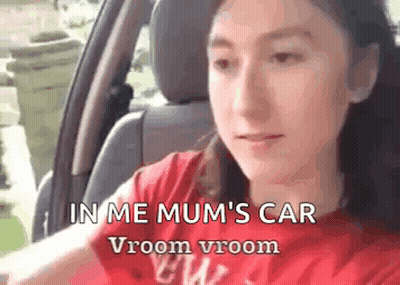 A Girl Is Sitting In The Driver 'S Seat Of A Car . GIF