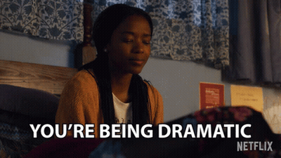 A Girl Is Sitting On A Bed With The Words You 'Re Being Dramatic Above Her GIF