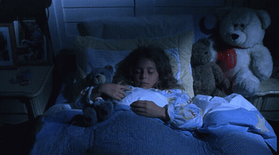 A Girl Is Sleeping In A Bed With Stuffed Animals GIF