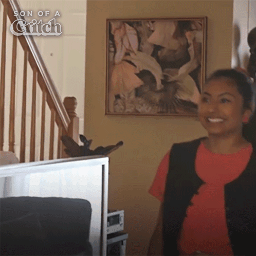 A Girl Is Smiling In Front Of A Painting Titled Son Of A Glitch GIF