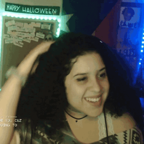 A Girl Is Smiling In Front Of A Sign That Says Happy Halloween GIF