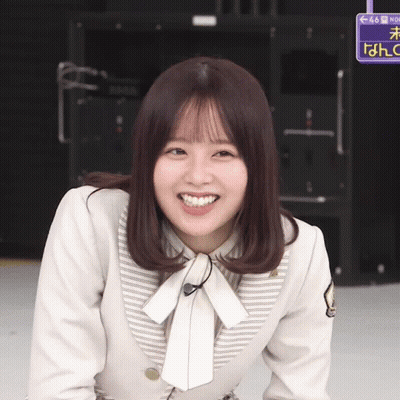 A Girl Is Smiling In Front Of A Sign That Says No GIF
