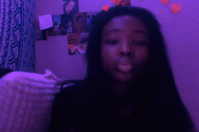 A Girl Is Smoking A Cigarette In Front Of A Purple Wall GIF