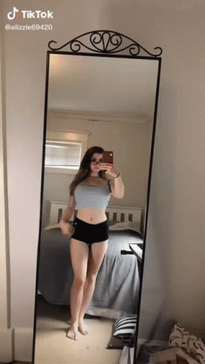 A Girl Is Taking A Selfie In Front Of A Mirror . GIF