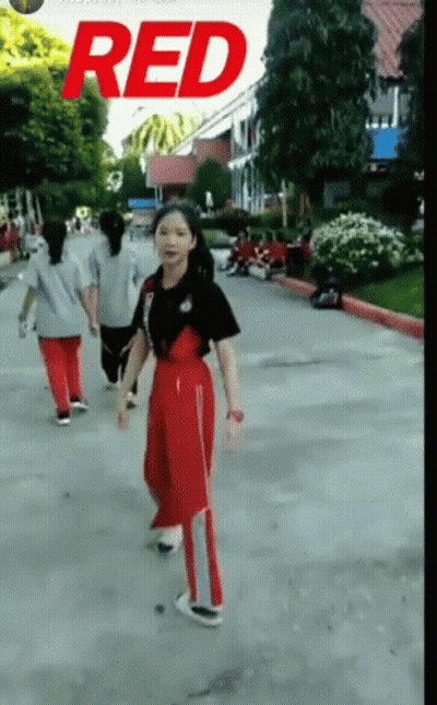 A Girl Is Walking Down A Street With The Word Red On The Bottom GIF