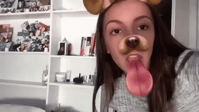 A Girl Is Wearing A Dog Mask With Her Tongue Out . GIF