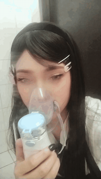 A Girl Is Wearing An Oxygen Mask And Holding A Device GIF