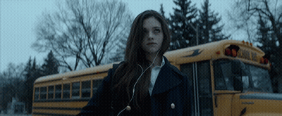 A Girl Standing In Front Of A School Bus GIF