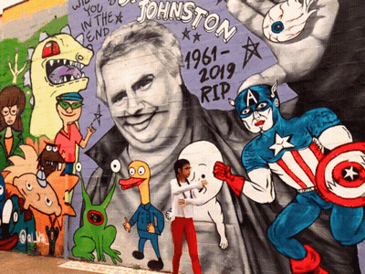 A Girl Stands In Front Of A Mural Of Johnston GIF