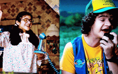 A Girl Talking On A Phone Next To A Boy Talking Into A Microphone GIF