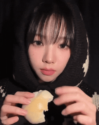 A Girl Wearing A Black And White Sweater Is Holding A Piece Of Cheese In Her Hands GIF