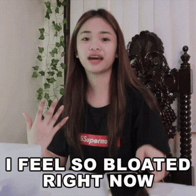 A Girl Wearing A Black Shirt That Says Supermo On It Says " I Feel So Bloated Right Now " GIF