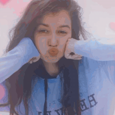A Girl Wearing A Blue Sweatshirt With The Letter H On It Blows A Kiss GIF