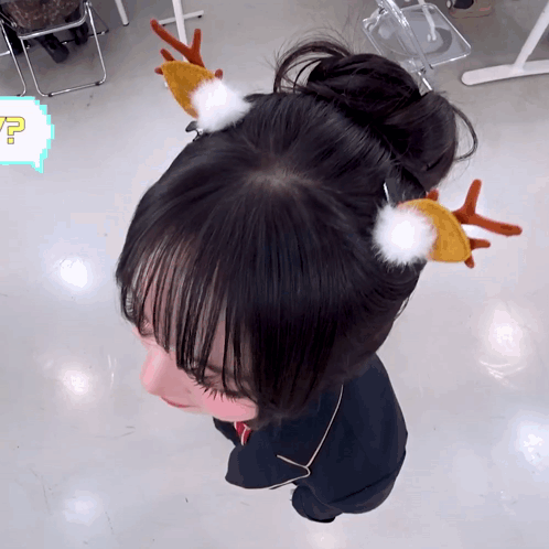 A Girl Wearing A Bun With Reindeer Antlers On Her Head GIF
