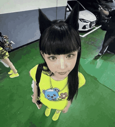 A Girl Wearing A Cat Ear Headband Is Standing In A Parking Garage . GIF