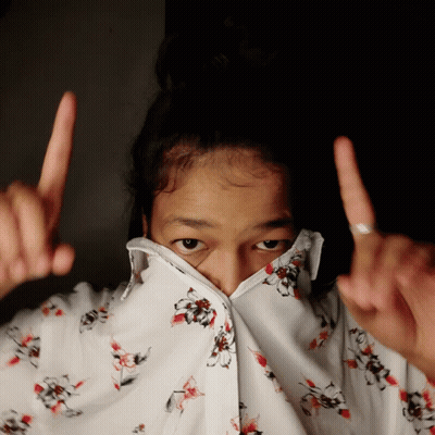 A Girl Wearing A Floral Shirt Covering Her Face With Her Fingers GIF