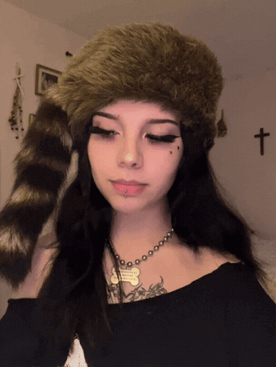 A Girl Wearing A Fur Hat And A Necklace With A Dog Tag That Says ' I Love You ' On It GIF