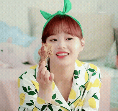 A Girl Wearing A Green Headband Is Holding A Piece Of Fried Chicken GIF