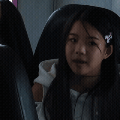 A Girl Wearing A Headband With The Letter N On It Sits In A Chair GIF