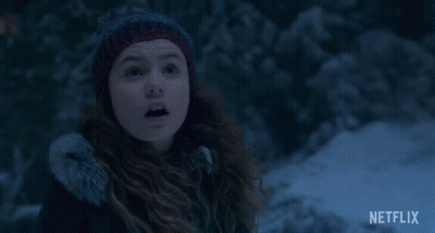 A Girl Wearing A Knitted Hat Is Smiling In The Snow With A Netflix Logo In The Corner GIF
