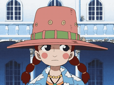 A Girl Wearing A Pink Hat With Circles On It Stands In Front Of A Building GIF
