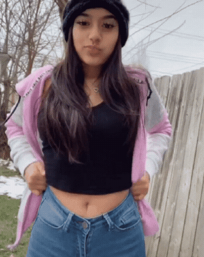 A Girl Wearing A Pink Hoodie And A Black Tank Top GIF