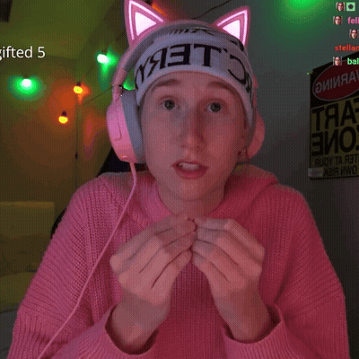 A Girl Wearing A Pink Sweater And Headphones Has A Sign That Says Gifted 5 GIF