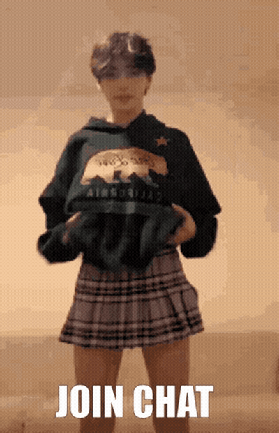 A Girl Wearing A Plaid Skirt And A California Sweatshirt Is Standing In Front Of A Sign That Says Join Chat GIF