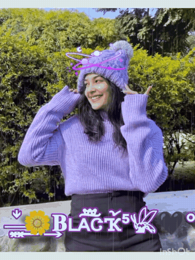A Girl Wearing A Purple Sweater And A Knitted Hat With The Word Black On It GIF
