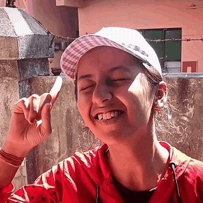 A Girl Wearing A Red Jacket And A White Hat Is Smiling GIF