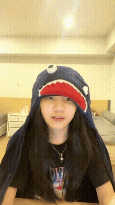 A Girl Wearing A Shark Hat And A Shirt That Says Devil On It GIF