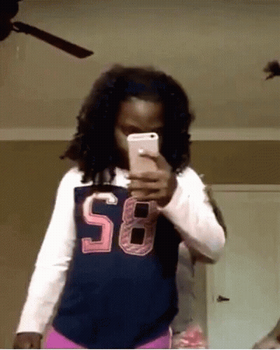 A Girl Wearing A Shirt With The Number 58 On It Takes A Selfie With Her Phone GIF