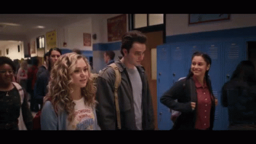 A Girl Wearing A T-Shirt That Says Powerful Shine Is Walking Down A Hallway GIF