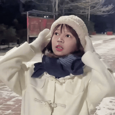 A Girl Wearing A White Hat And Scarf Holds Her Hands To Her Head GIF