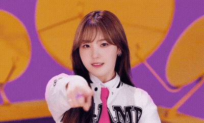 A Girl Wearing A White Jacket And A Pink Tie Points At The Camera . GIF