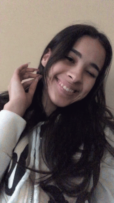 A Girl Wearing A White Sweatshirt With The Letter W On It Smiles For The Camera GIF