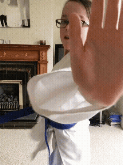 A Girl Wearing Glasses And A Blue Belt Is Making A Stop Gesture GIF