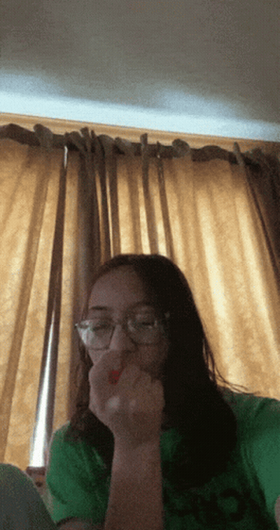 A Girl Wearing Glasses And A Green Shirt Eating A Red Strawberry GIF