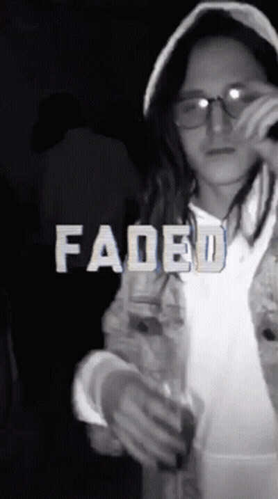 A Girl Wearing Glasses And A Hooded Jacket With Faded Written In White Letters GIF