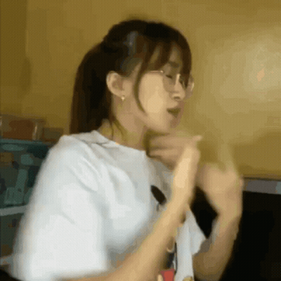 A Girl Wearing Glasses And A White Shirt Is Making A Funny Face . GIF
