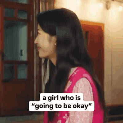 A Girl Who Is Going To Be Okay Is Standing In Front Of A Door And Smiling . GIF