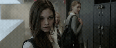 A Girl With A Backpack Is Standing In A Hallway GIF