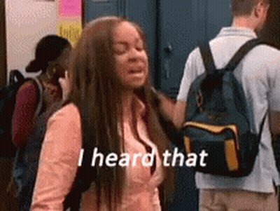 A Girl With A Backpack Is Standing In Front Of A Group Of People And Saying `` I Heard That '' . GIF