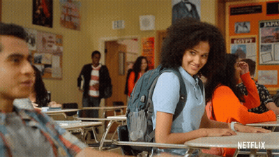 A Girl With A Backpack Sits At A Desk In A Classroom With A Sign That Says Egypt On It GIF