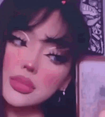 A Girl With A Bandana On Her Head Is Taking A Selfie In Front Of A Mirror . GIF