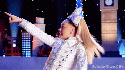 A Girl With A Bow In Her Hair Is Pointing At Something In Front Of A Big Ben GIF