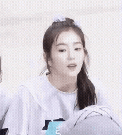 A Girl With A Ponytail And A Bow In Her Hair Is Wearing A White Shirt . GIF