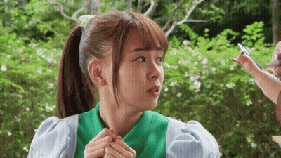 A Girl With A Ponytail And A Green Shirt Is Looking At Something GIF